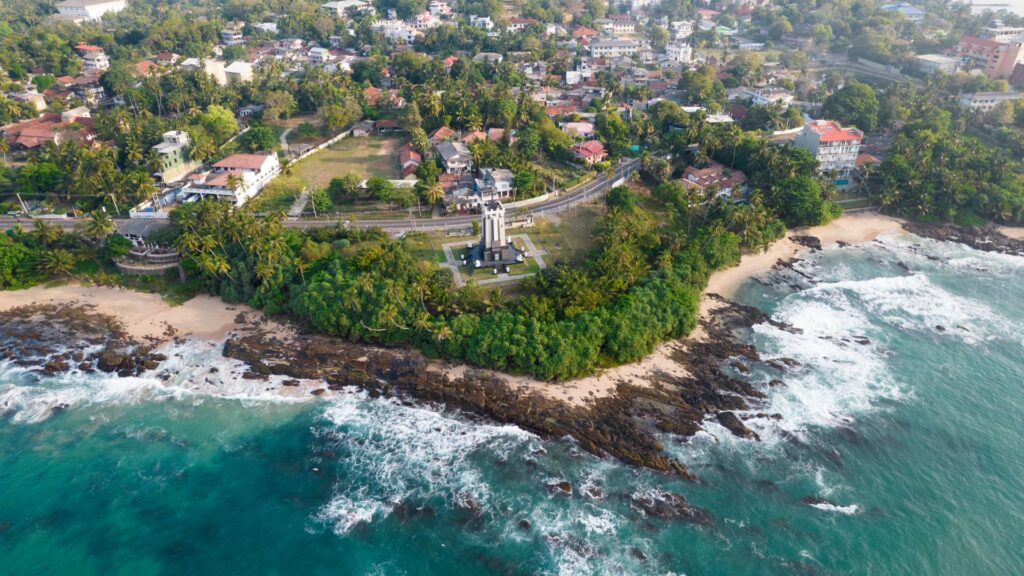 drone picture of a lighthouse on the side of the road in sri lanka