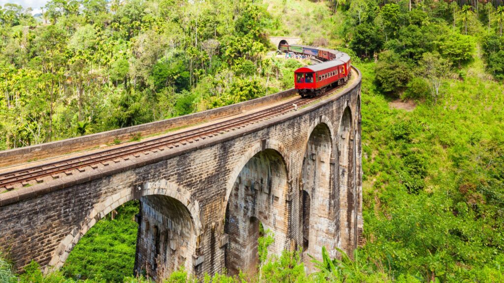 famous tourist attraction in ella showing a train passing over the 9 arches bridge. 