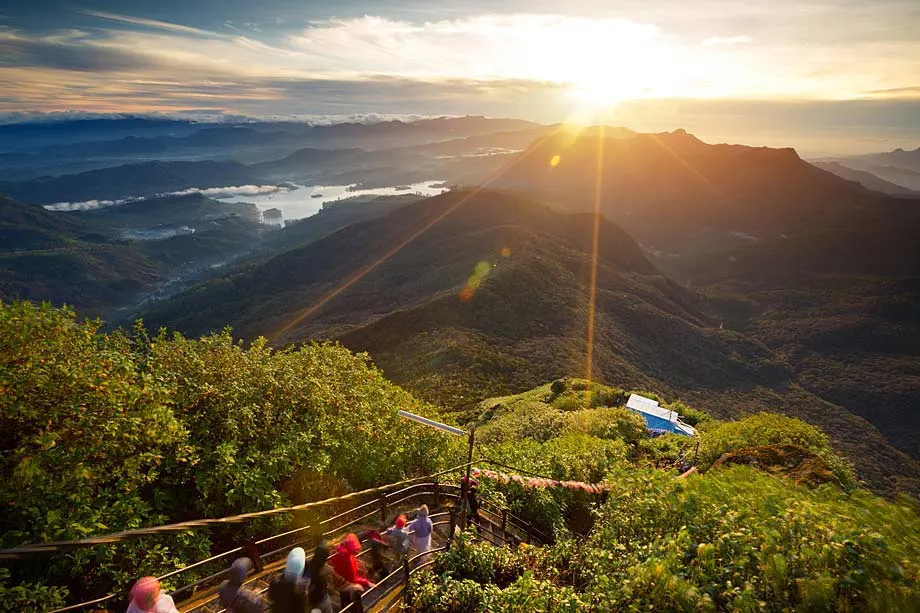 Pilgrims and travelers hiking at Adam’s Peak under the glow of sunrise.