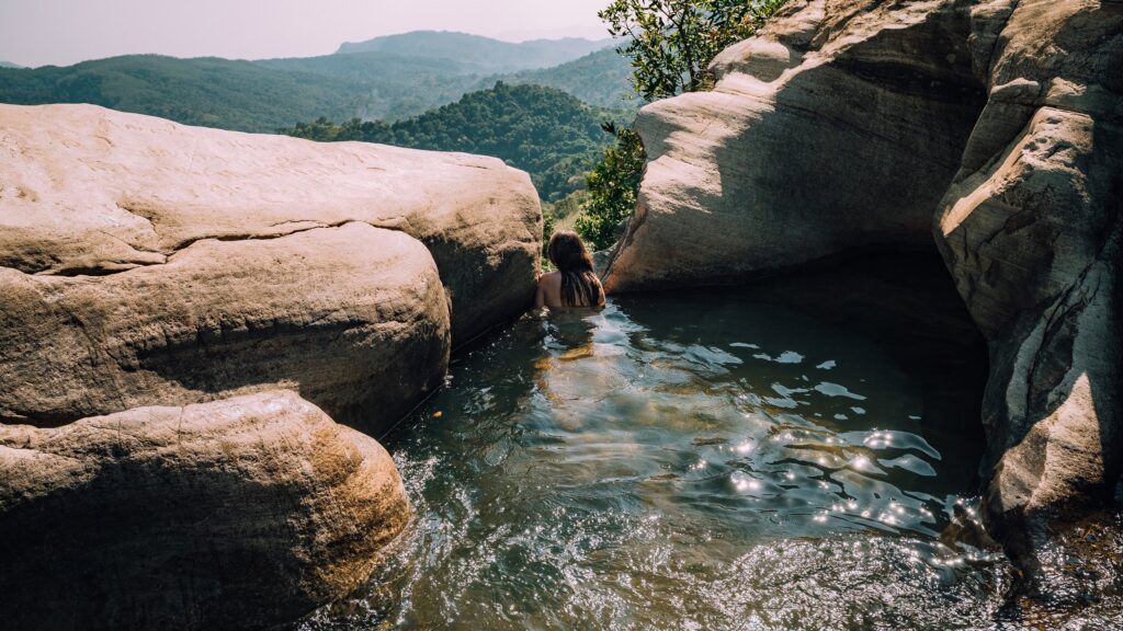 Traveler relaxing in the natural infinity pools of Diyaluma Falls, Sri Lanka.